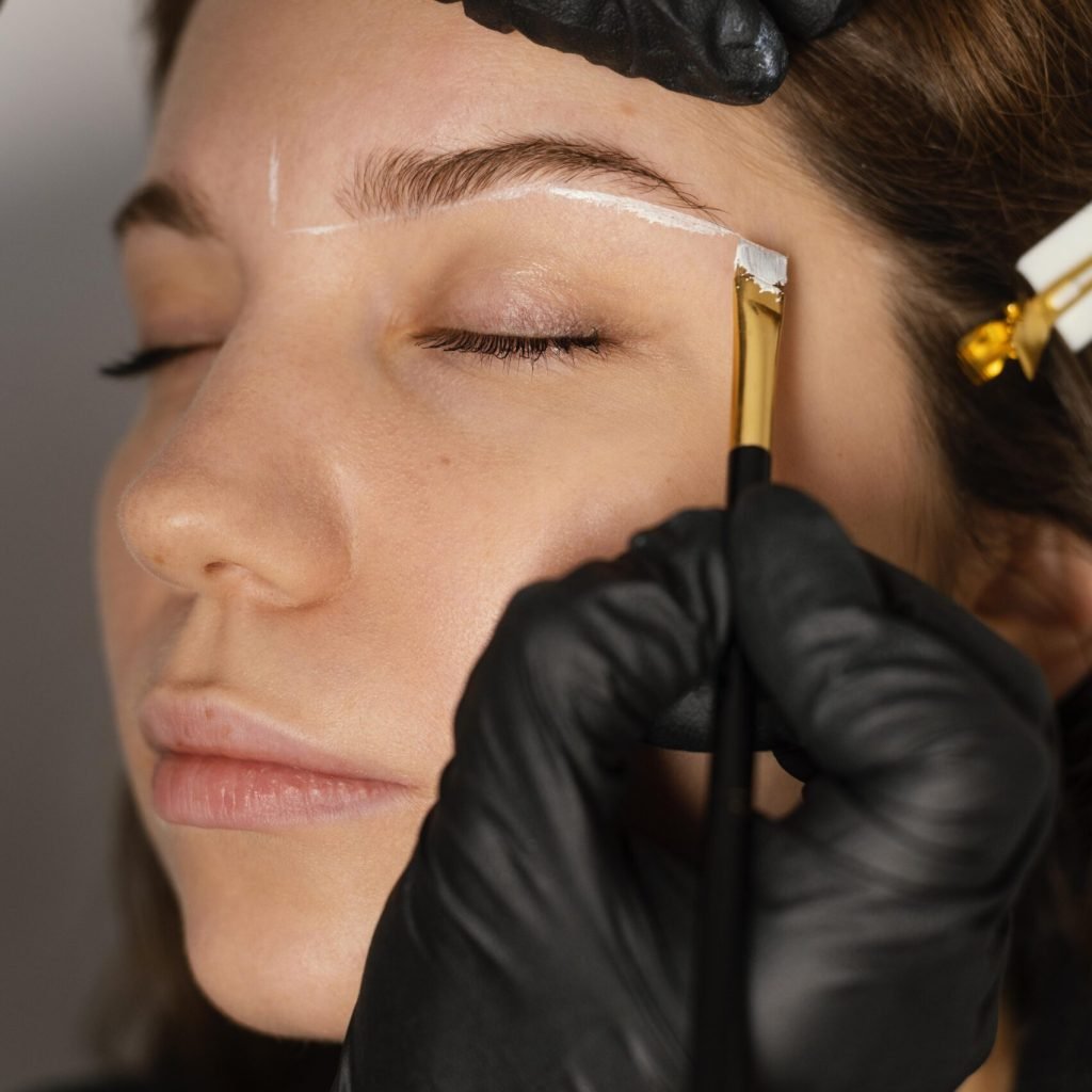 woman getting eyebrow treatment from beautician